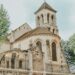 Église romane en pierre avec clocher carré, entourée d’arbres